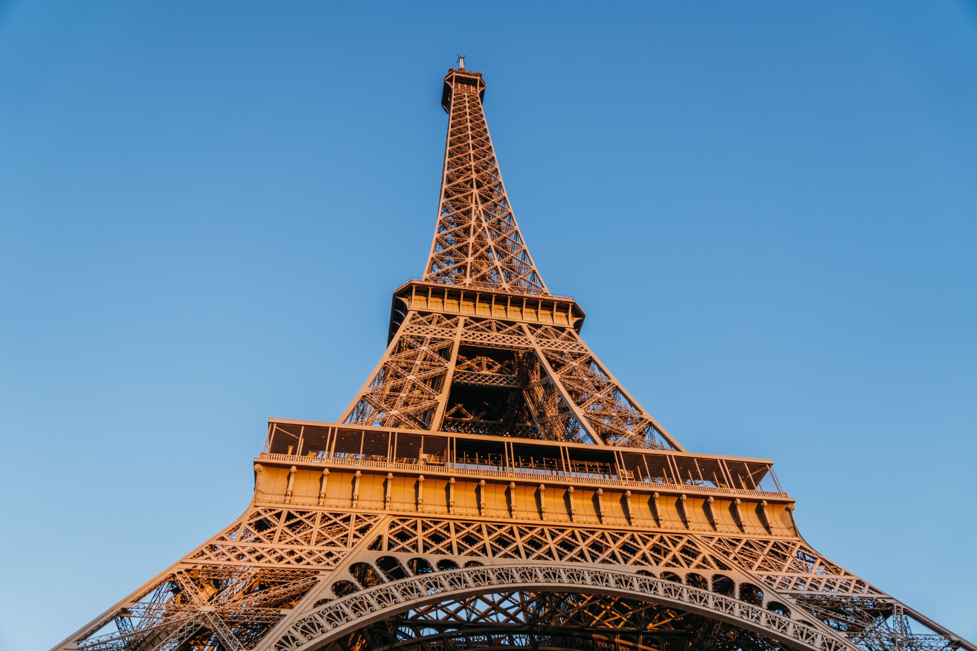 Looking upward through the Eiffel Tower's iron lattice and first-floor platform