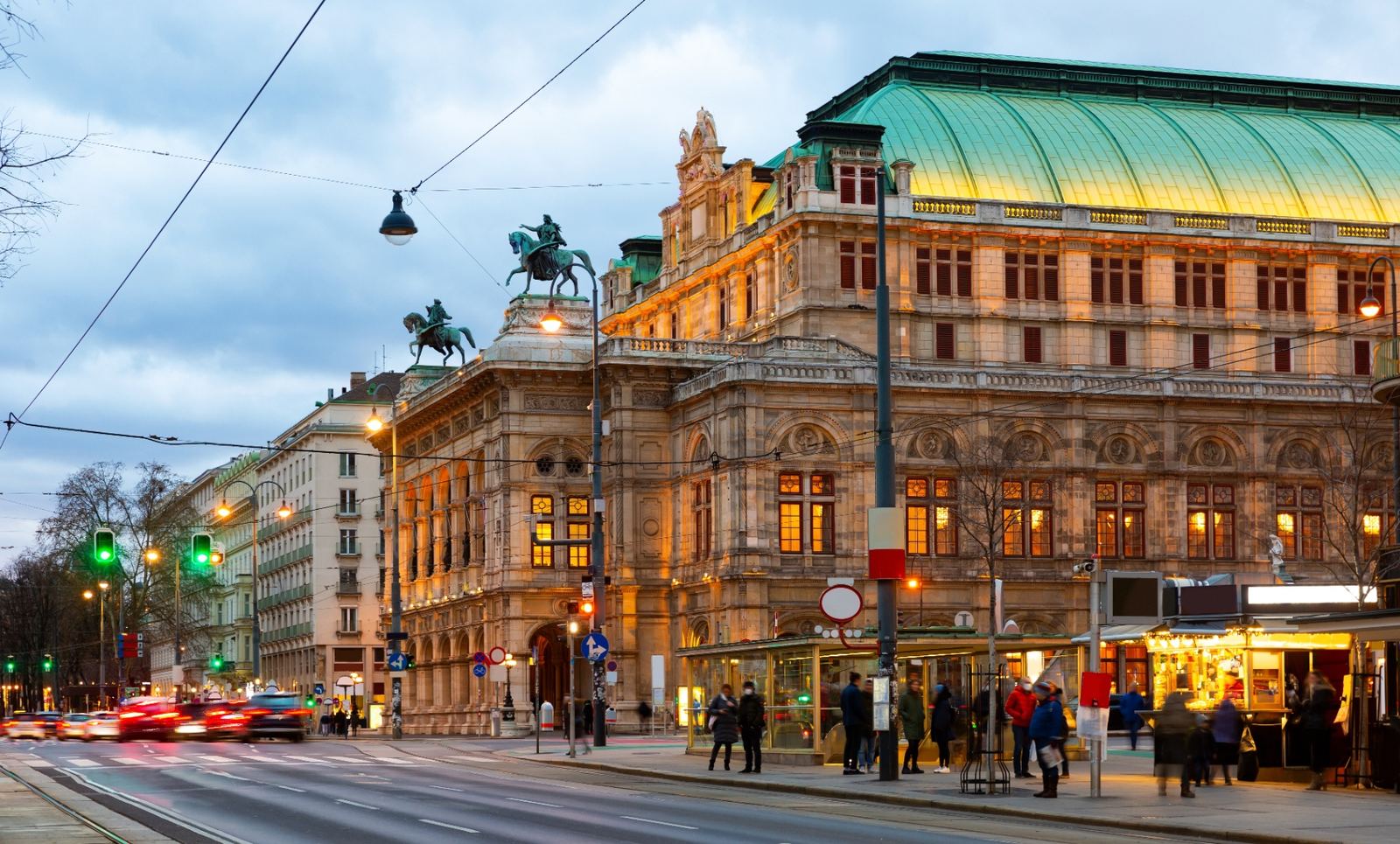 Vienna State Opera at dusk with its illuminated Renaissance Revival facade and green copper roof on the Ringstrasse