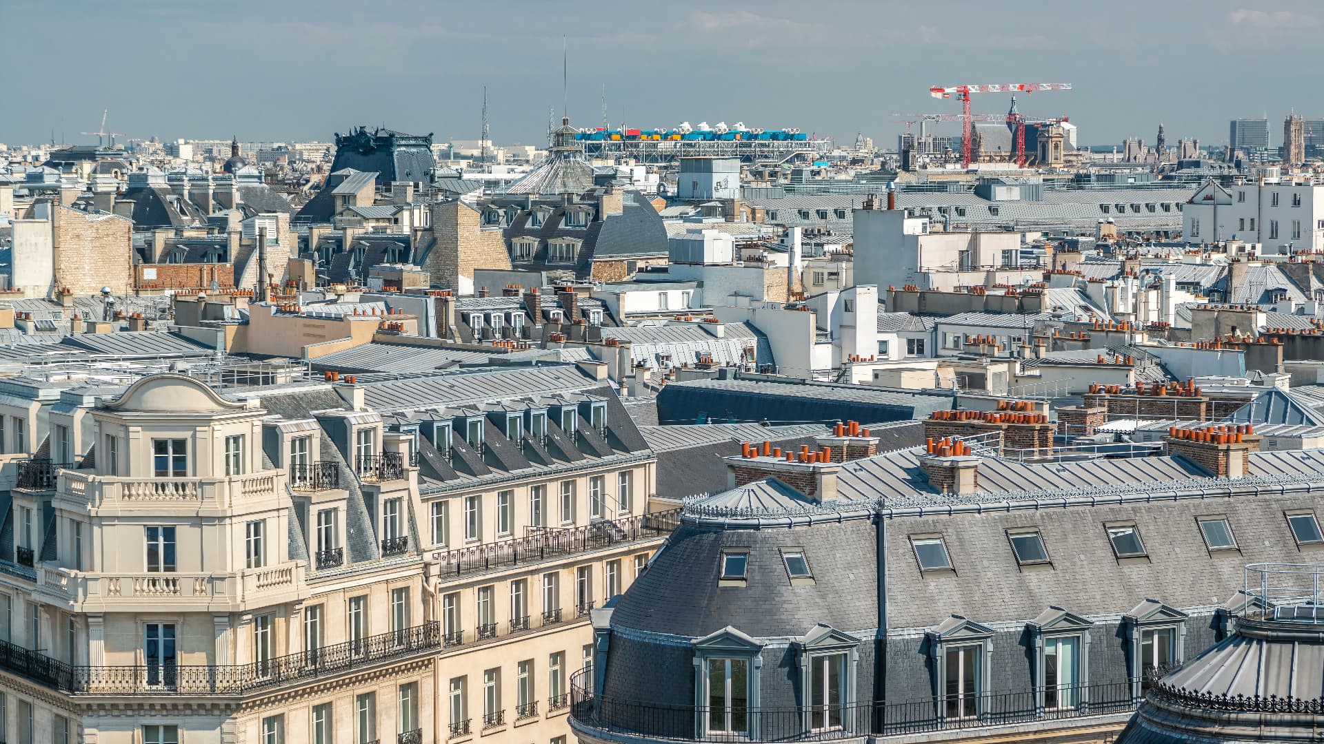 Panorama of Paris rooftops from the Galeries Lafayette terrace with the Grand Palais glass roof in the distance