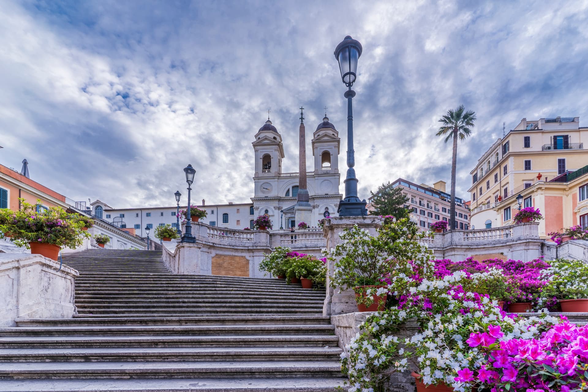 Quiet Spanish Steps with azaleas and street lamps under a cloudy sky