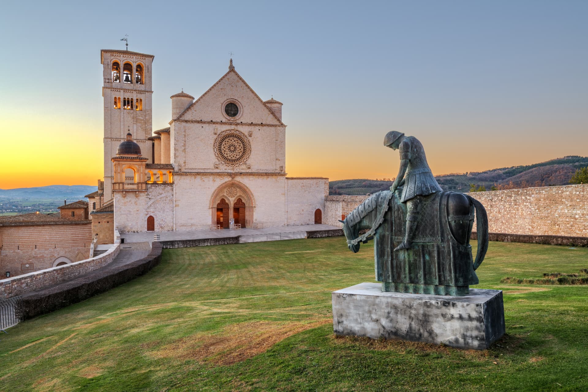 The facade and bell tower of the Basilica of Saint Francis in Assisi at sunset