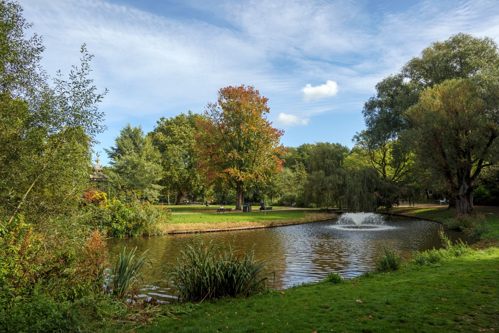 The central pond and fountain in Sarphatipark, Amsterdam, surrounded by trees in early autumn colour