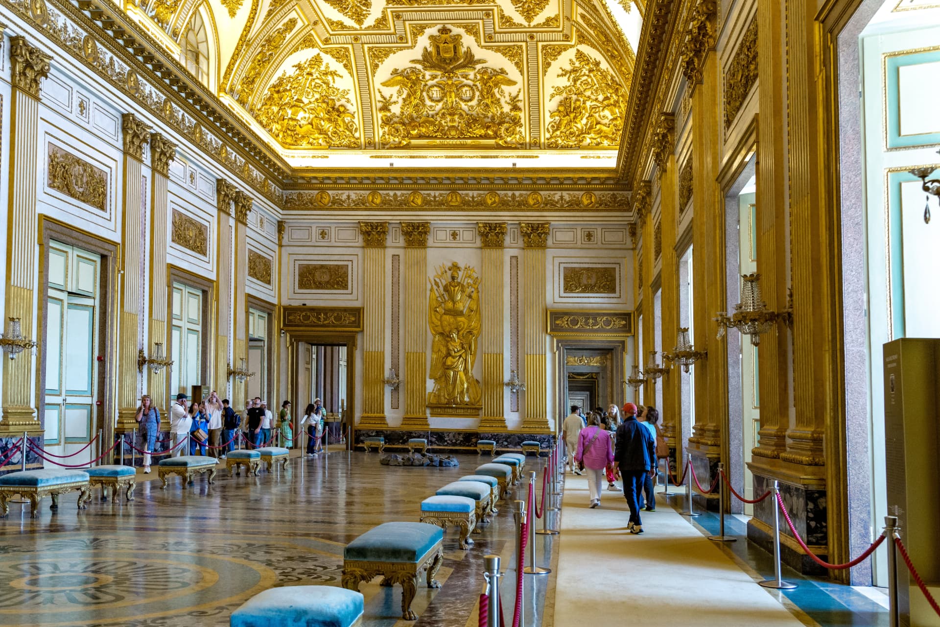 Gilded throne room inside the Royal Palace of Caserta with a golden ceiling, columns and a marble floor
