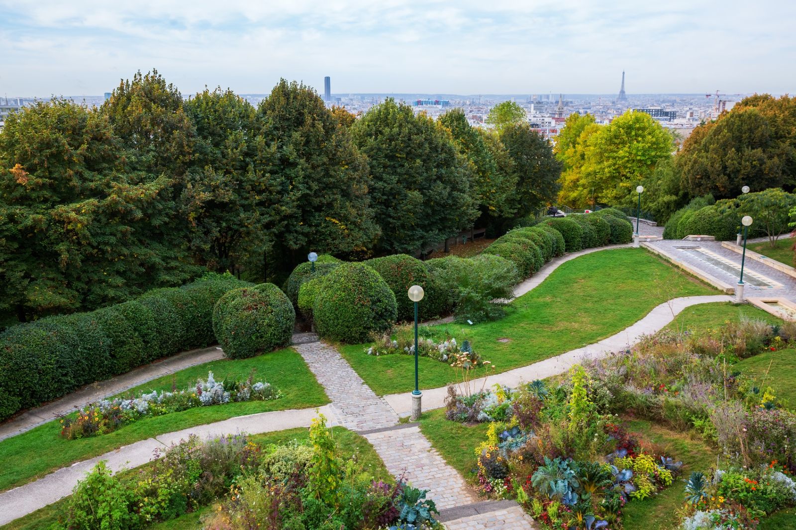 Parc de Belleville gardens with winding paths and a panoramic view of the Paris skyline toward the Eiffel Tower