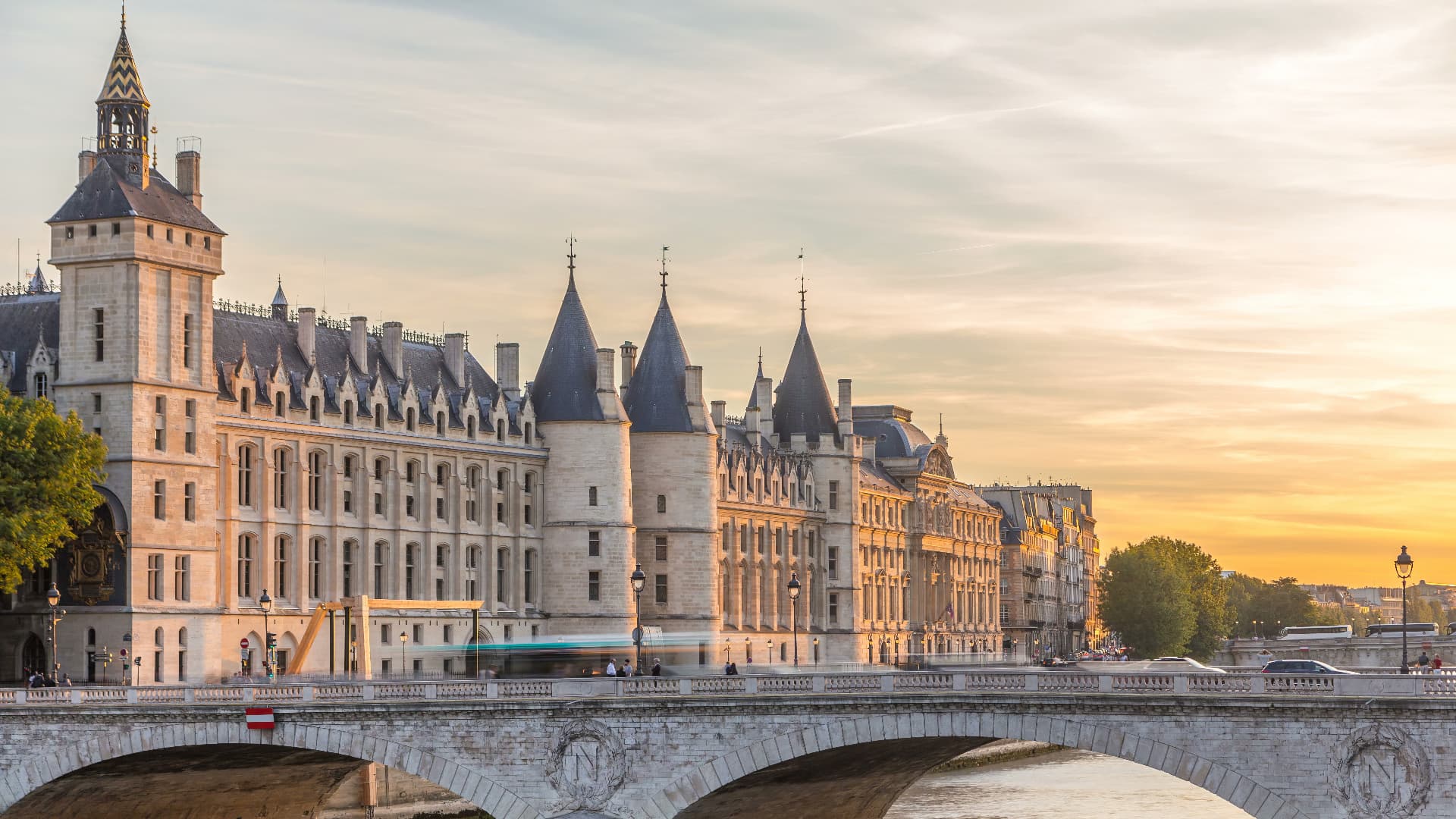 The Conciergerie's towers and clock tower above the Seine seen from a bridge at golden hour