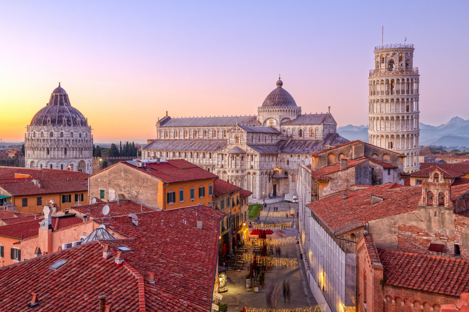 Pisa’s Piazza dei Miracoli at dusk with the Baptistery, Cathedral and Leaning Tower above the rooftops