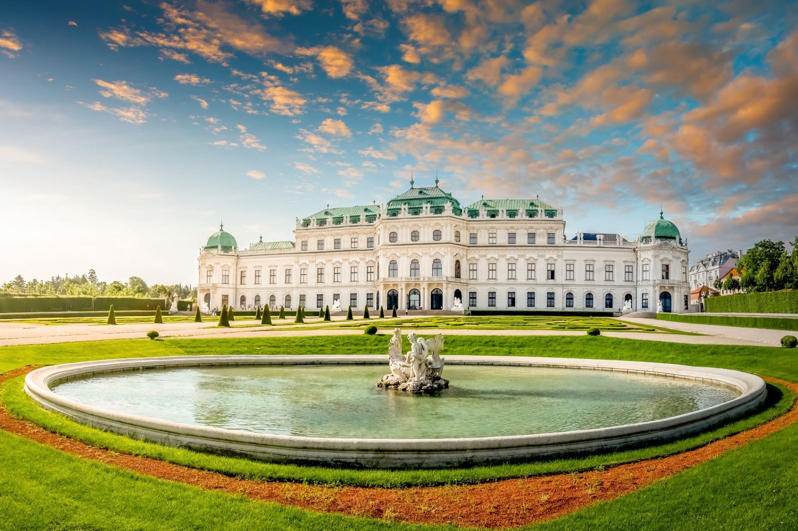 Belvedere Palace in Vienna at sunset with its Baroque white facade, green copper domes, formal gardens and a central fountain