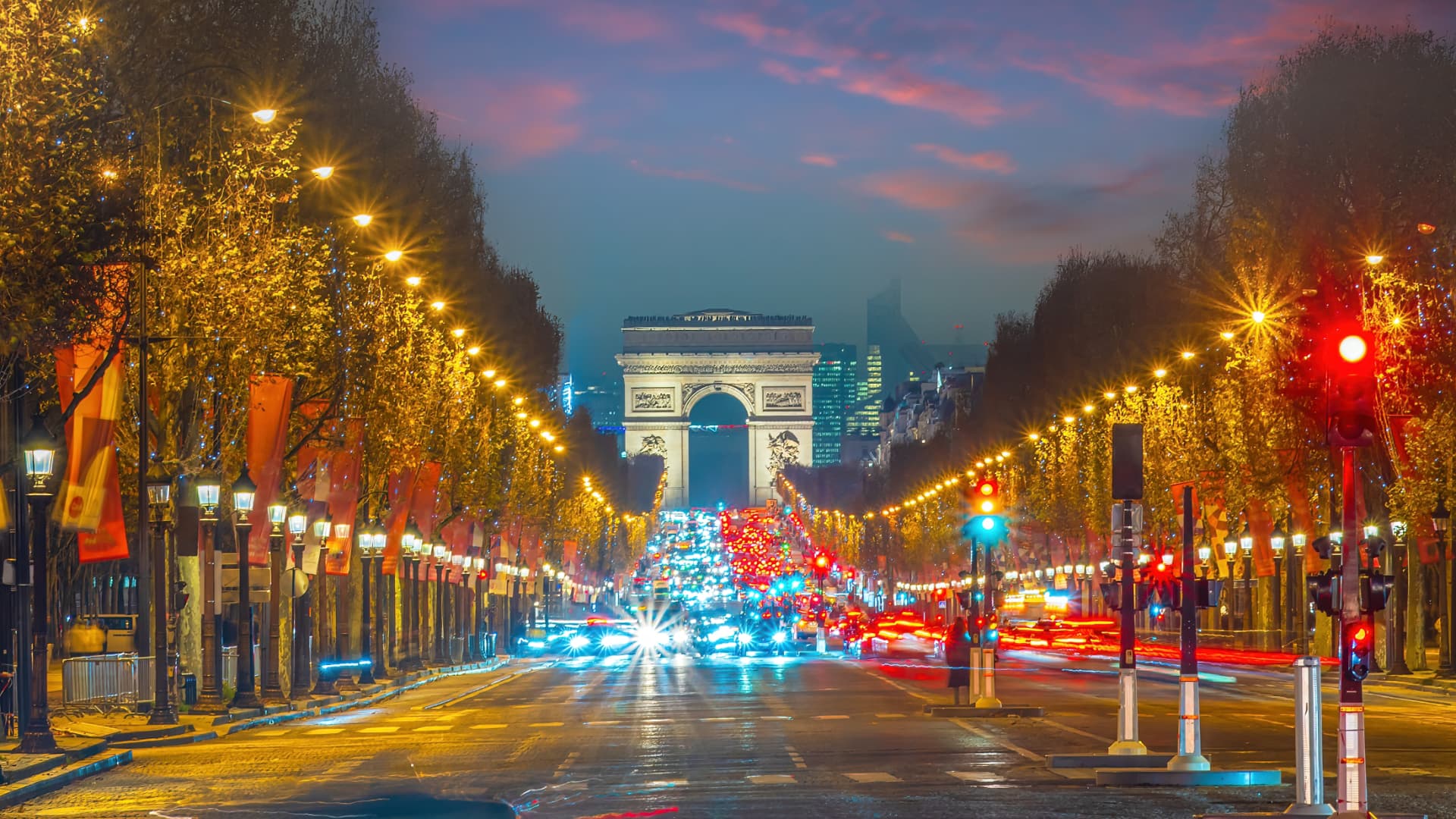 Arc de Triomphe seen along the lit Champs-Élysées at dusk
