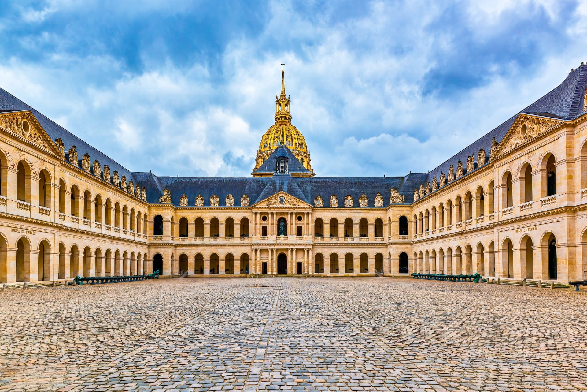 The arcaded Cour d'Honneur courtyard at Les Invalides with the gilded dome behind