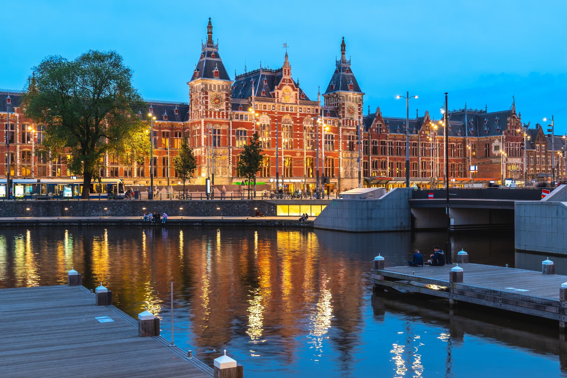 Amsterdam Centraal Station lit up at dusk and reflected in the water