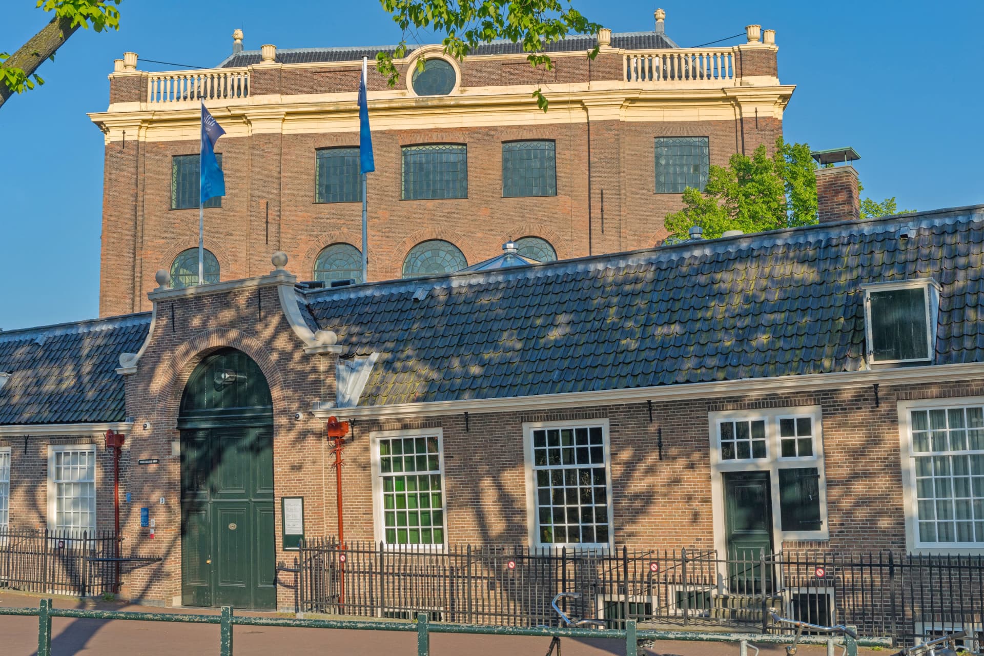 The brick exterior of the Portuguese Synagogue in Amsterdam with its arched windows and the low annex buildings in front