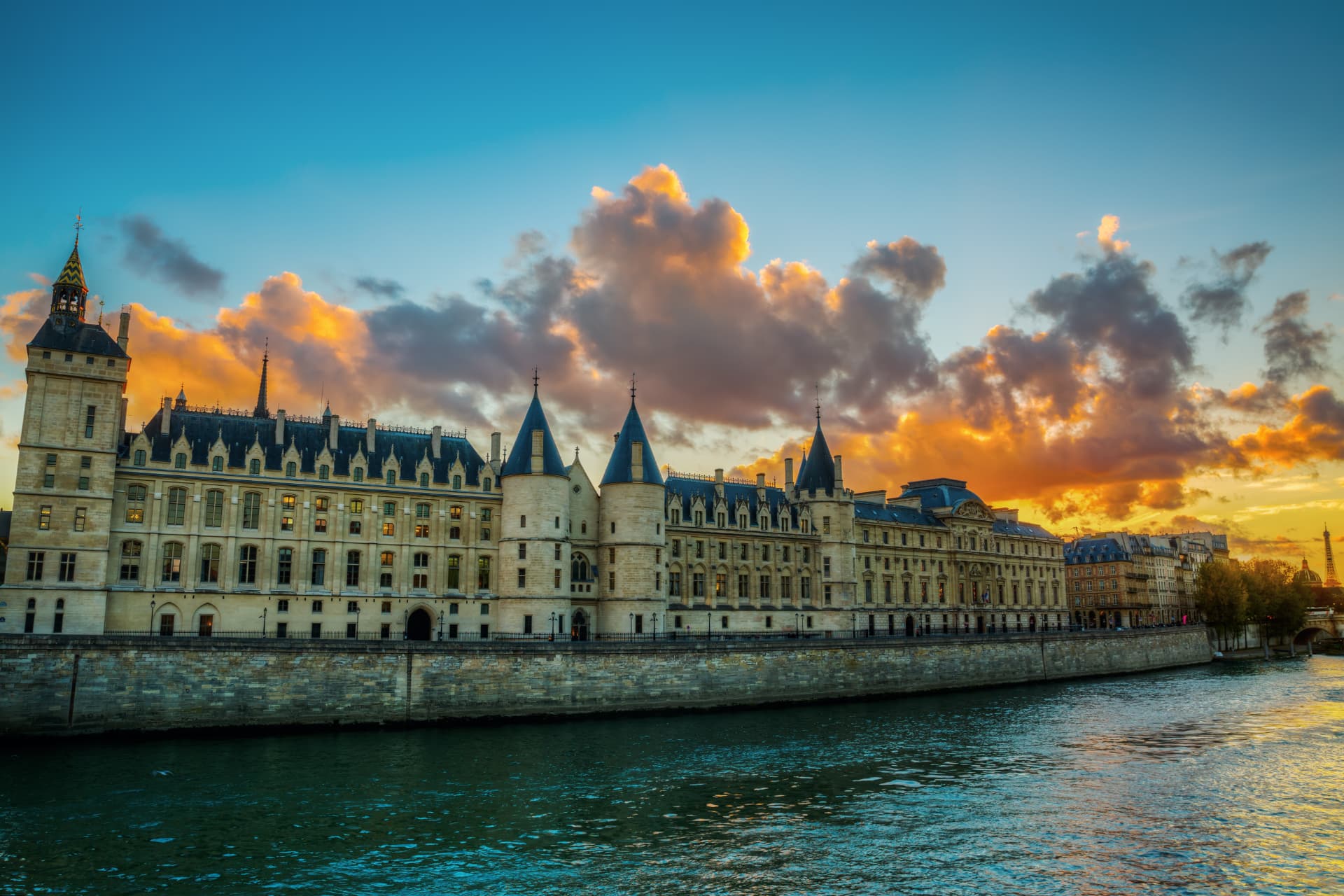The Conciergerie on the Île de la Cité seen from the Seine at sunset with its towers and clock tower