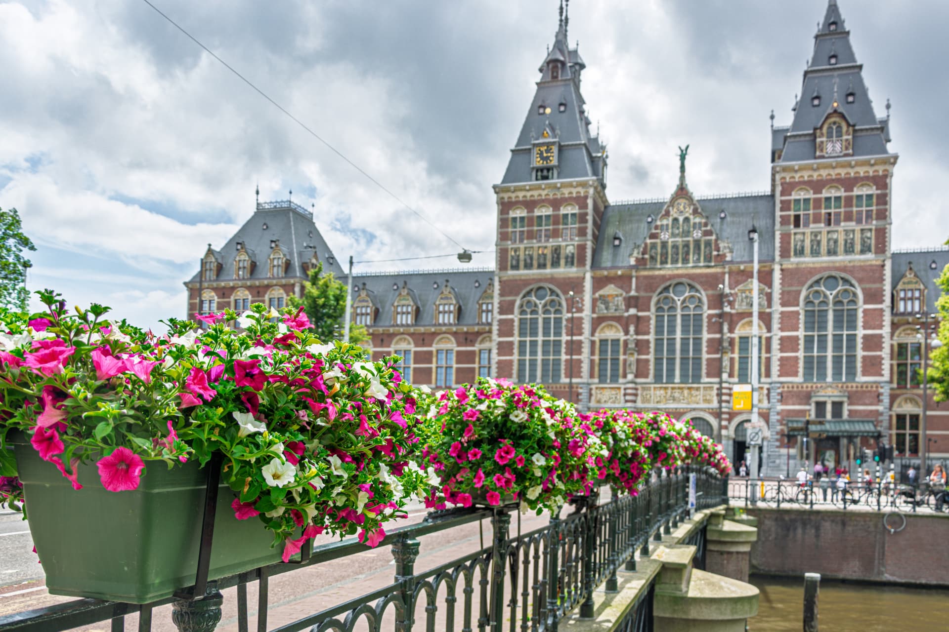 Flower boxes on a canal bridge with the Rijksmuseum's towers in the background