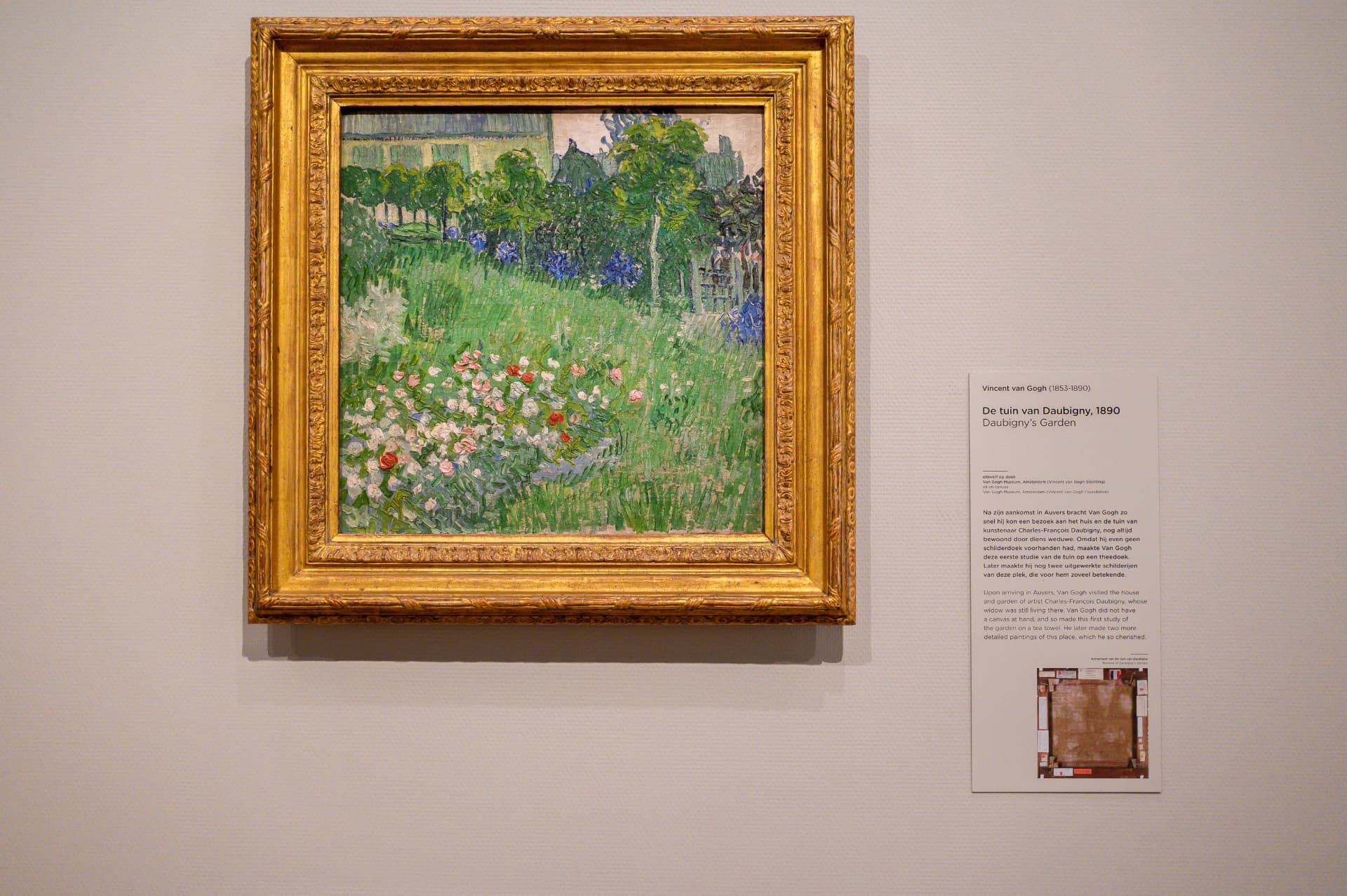 Van Gogh's painting Daubigny's Garden in a gilded frame on the wall of the Van Gogh Museum, with its label beside it
