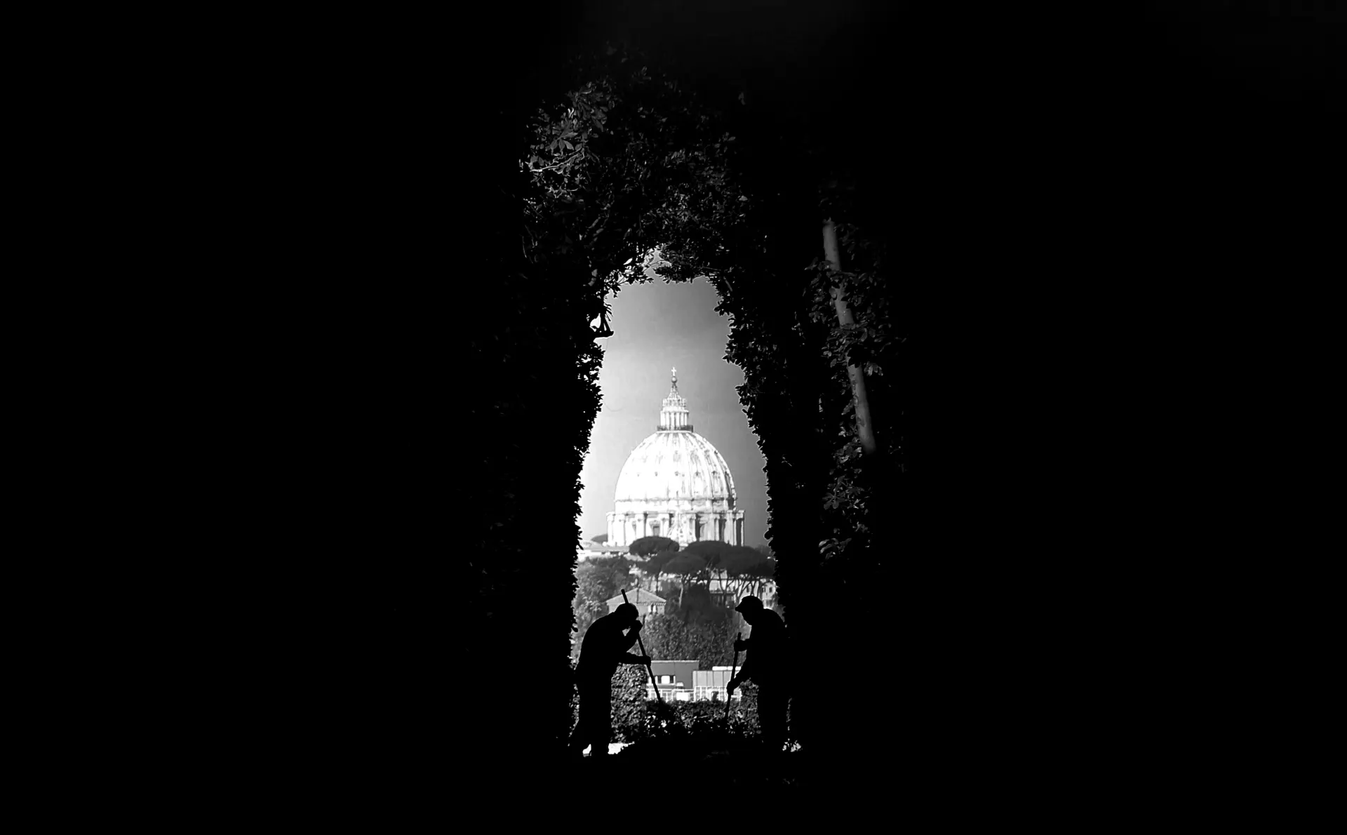 The famous Aventine Keyhole view in Rome 2026 — St. Peter's Basilica dome perfectly framed through a tree-lined hedge tunnel inside the gardens of the Knights of Malta priory, seen through the bronze keyhole of the green oak door