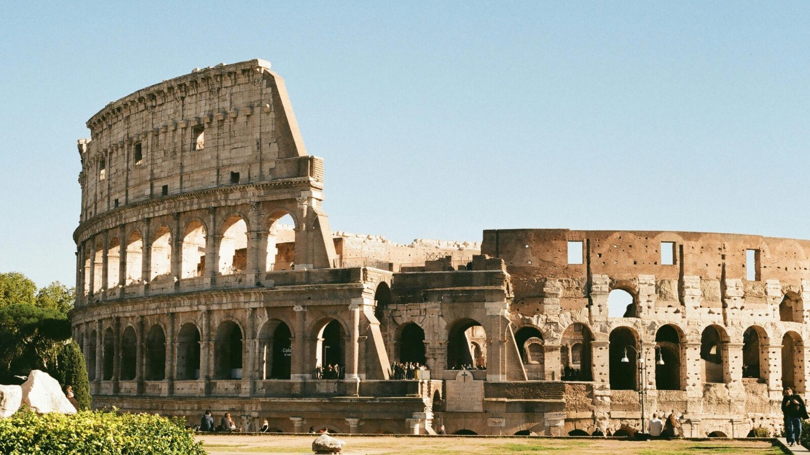 Colosseum south side in Rome 2026 — showing both preserved arched façade and exposed inner brick walls with visitors at ground level