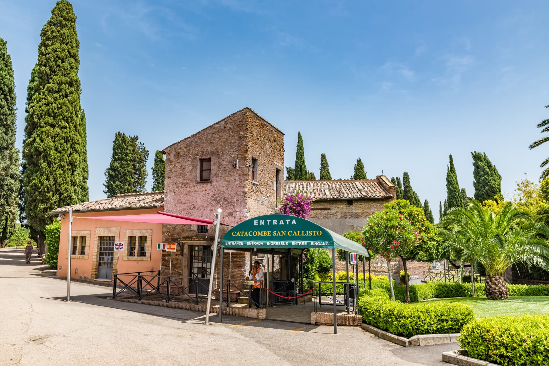 Entrance to the Catacombe di San Callisto on the Appian Way in Rome, with the green Entrata canopy, cypress trees and the brick gatehouse
