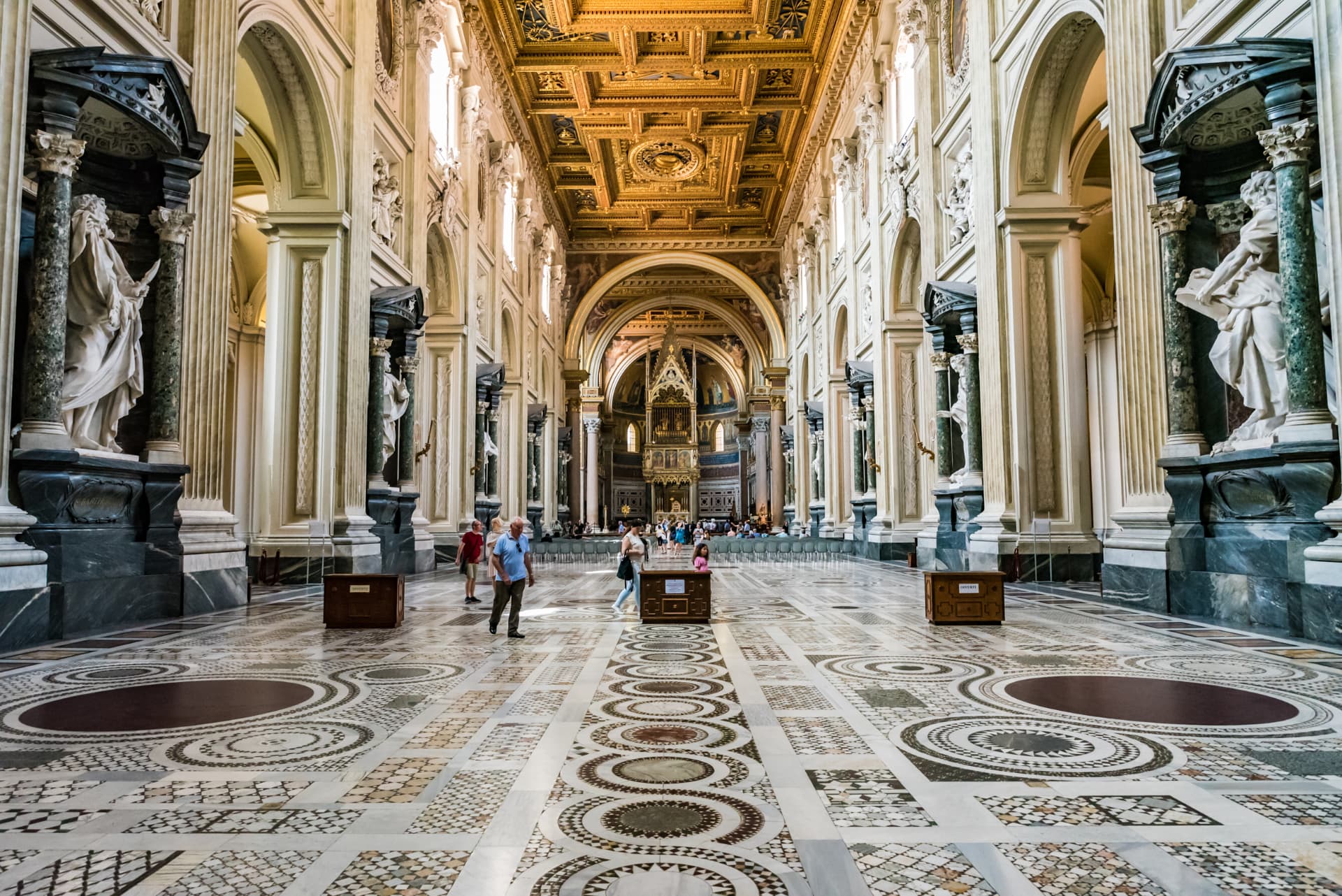 The central nave of San Giovanni in Laterano with Borromini's Baroque design, gilded coffered ceiling, Cosmatesque floor and apostle statues in the nave niches