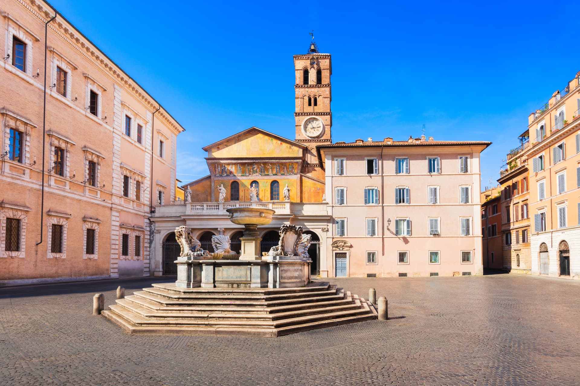 Piazza di Santa Maria in Trastevere in Rome with the octagonal fountain in the foreground and the basilica facade mosaic and Romanesque bell tower behind