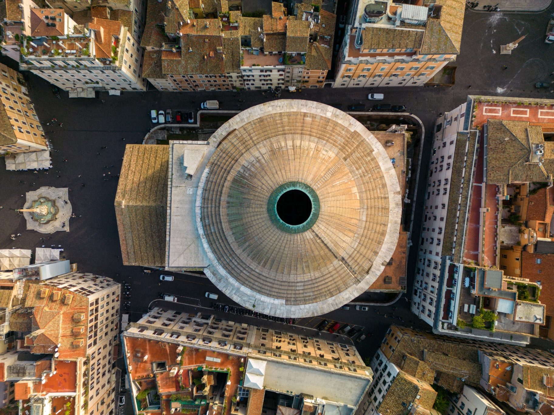 Aerial top-down view of the Pantheon dome and central oculus surrounded by Rome's terracotta rooftops