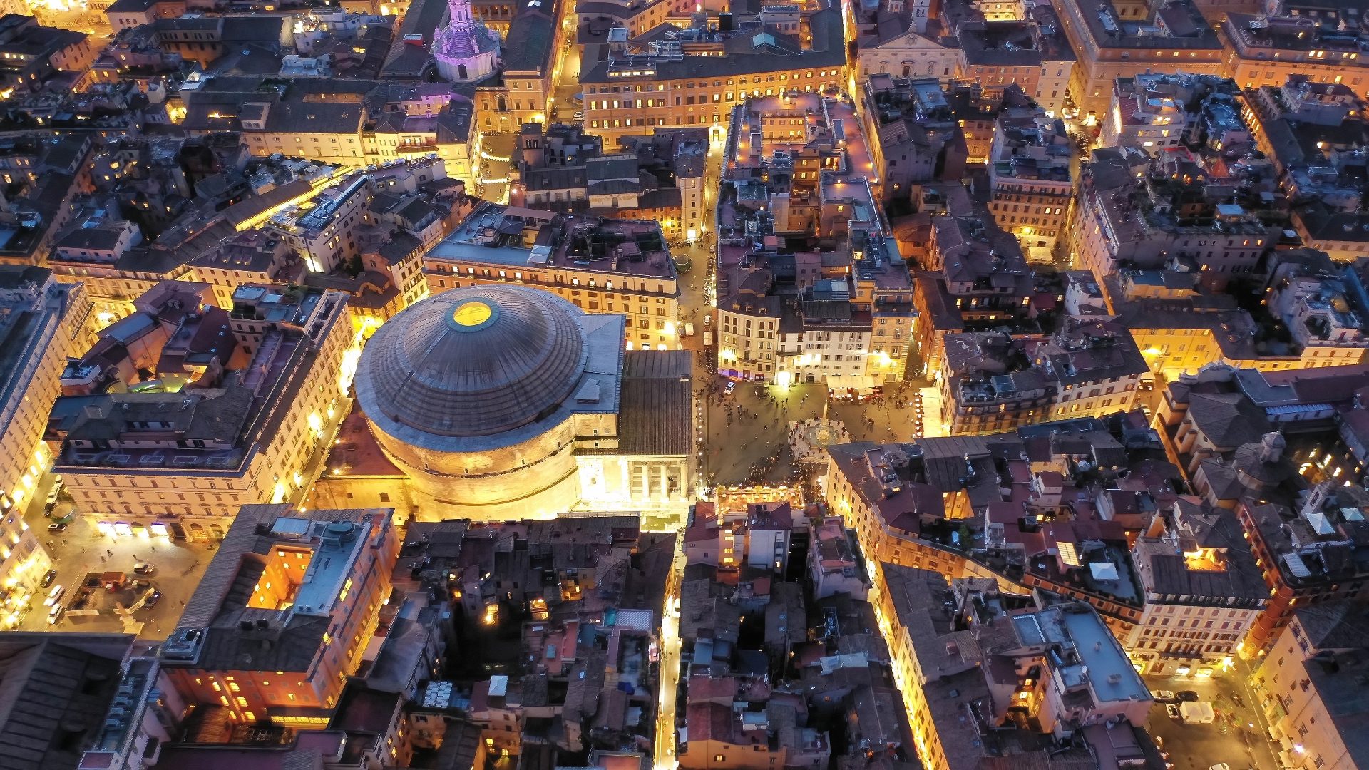 Aerial night view of the Pantheon's lit dome and Piazza della Rotonda surrounded by glowing Rome streets