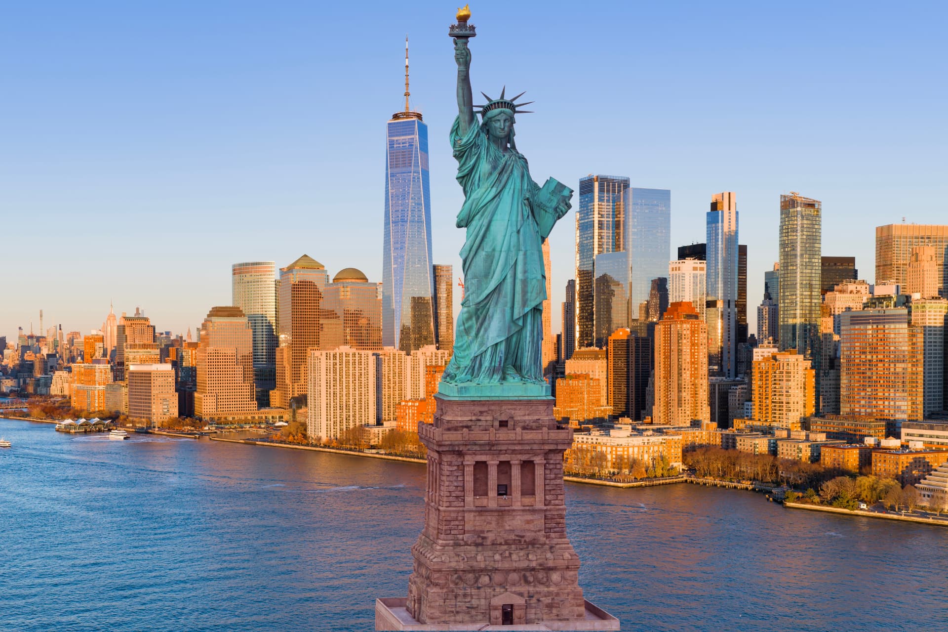 Aerial view of the Statue of Liberty with One World Trade Center and the Lower Manhattan skyline behind, the Hudson River in the foreground