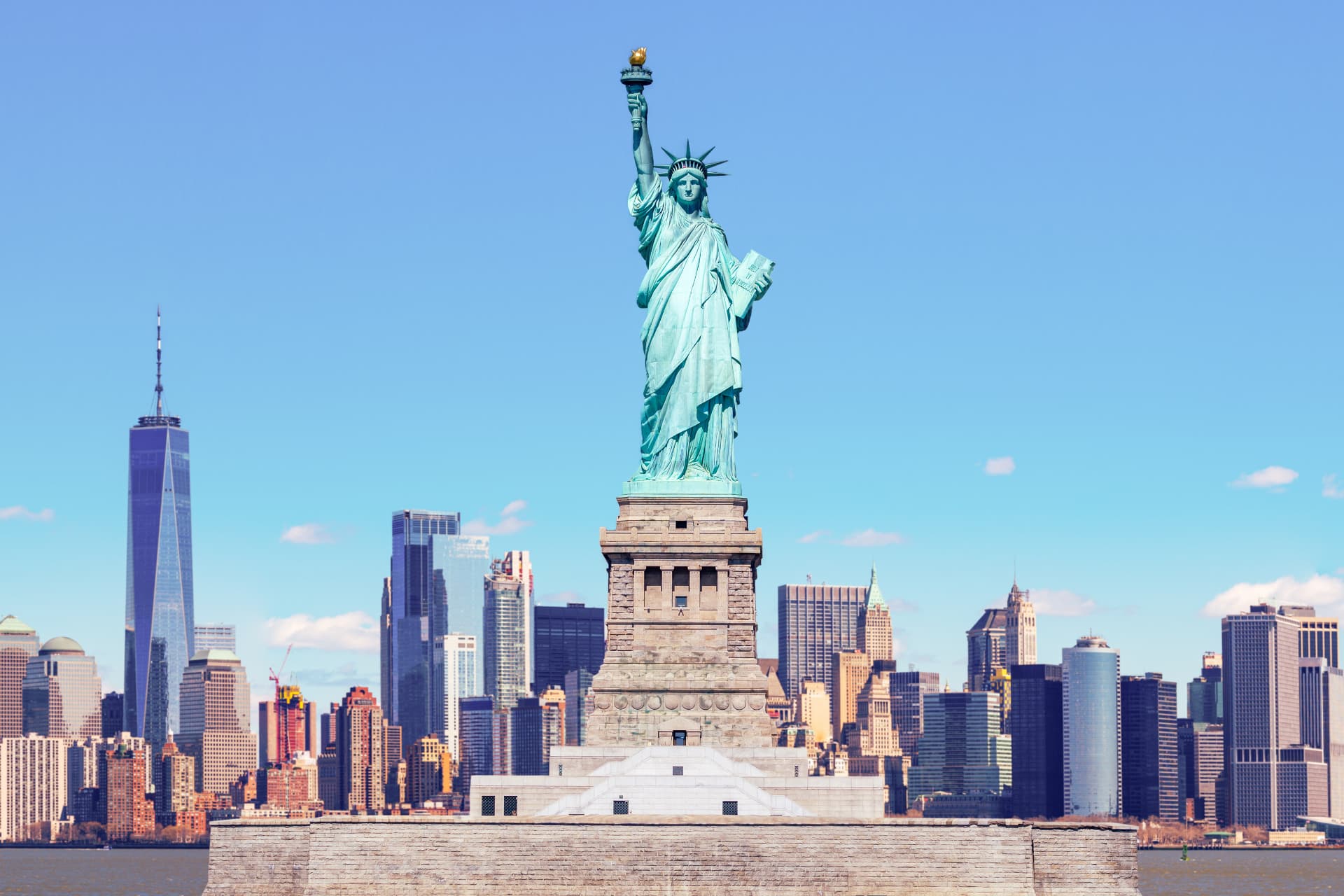 The Statue of Liberty on its pedestal in front of the Lower Manhattan skyline, with One World Trade Center to the left